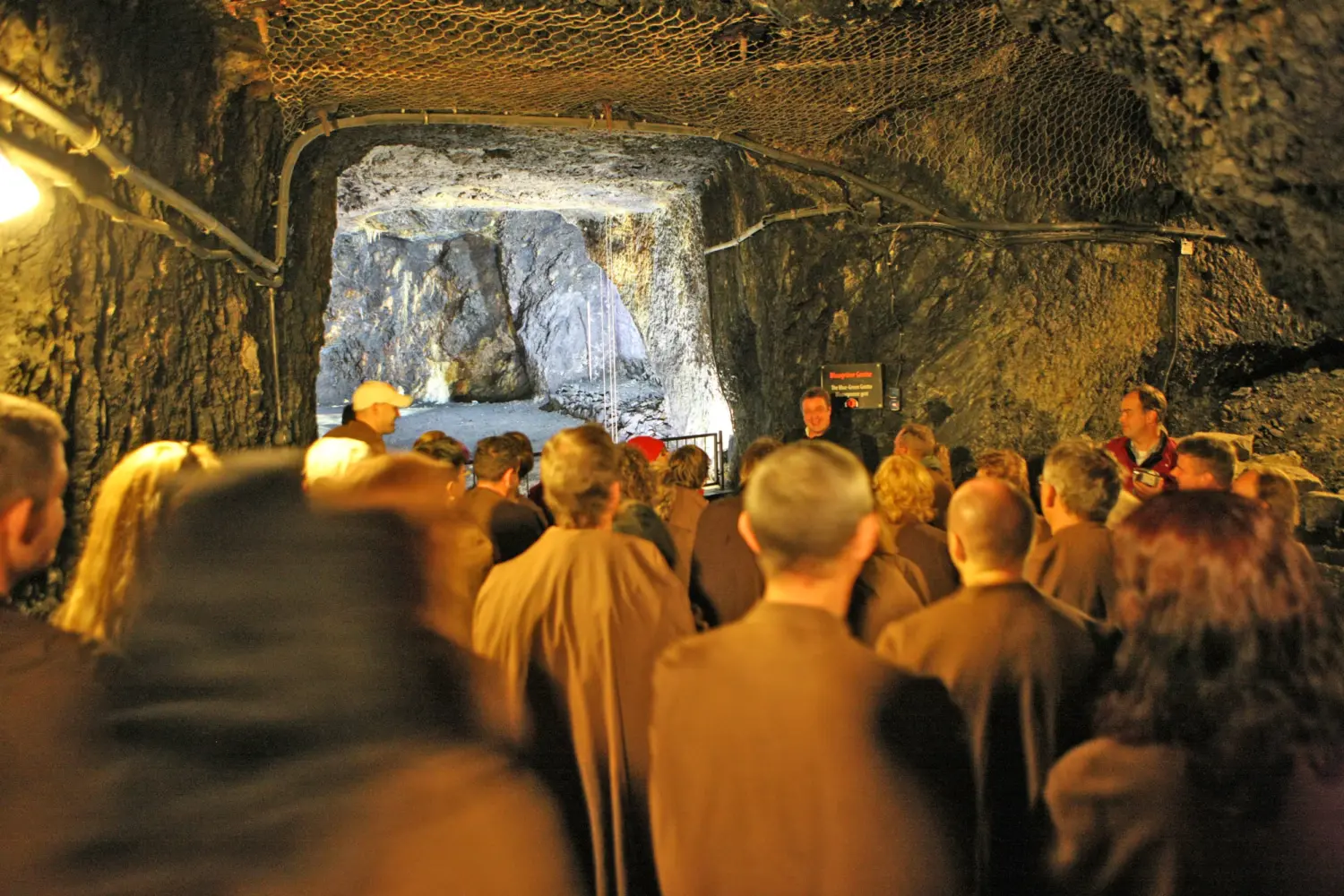 Eine Gästegruppe steht vor einer Grotte.