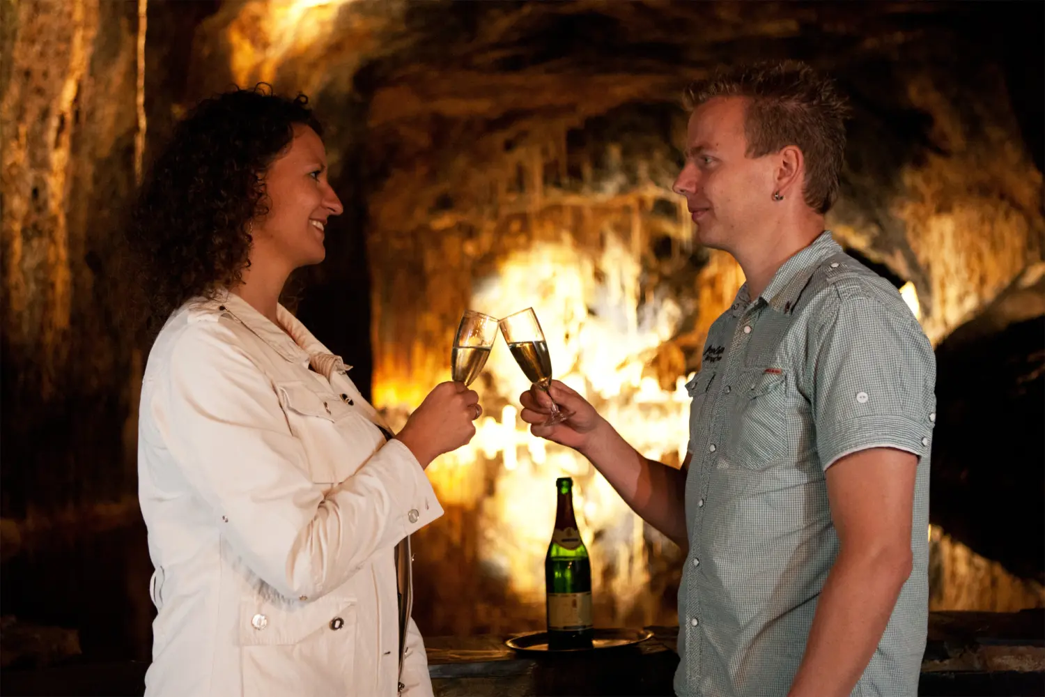 Ein Paar stößt mit einem Glas Sekt im Märchendom der Saalfelder Feengrotten an