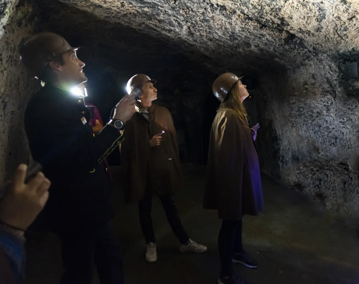 Eine Gruppe leuchtet im Schaubergwerk Feengrotten mit Taschenlampen