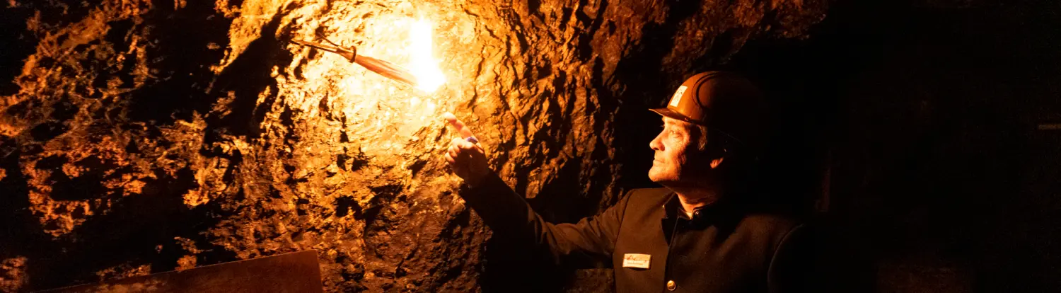 Ein Grottenführer zeigt auf eine Laterne im Schaubergwerk Saalfelder Feengrotten